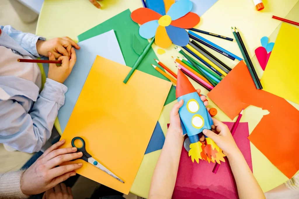 Picture of children cutting construction paper and doing STEAM activities for preschoolers at home.