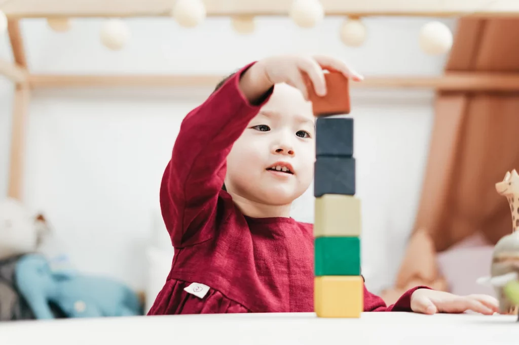 Picture of a young girl learning STEM vs STEAM while playing with blocks at a preschool in Raleigh