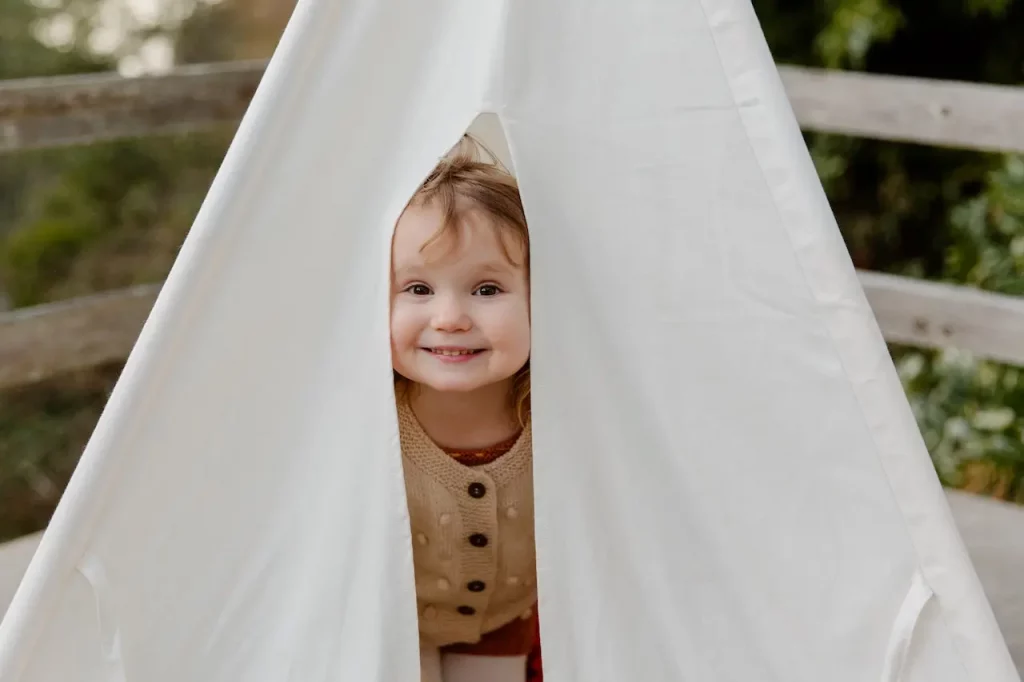 Picture of a happy child in a tent featured on the article for preschooler emotional development.