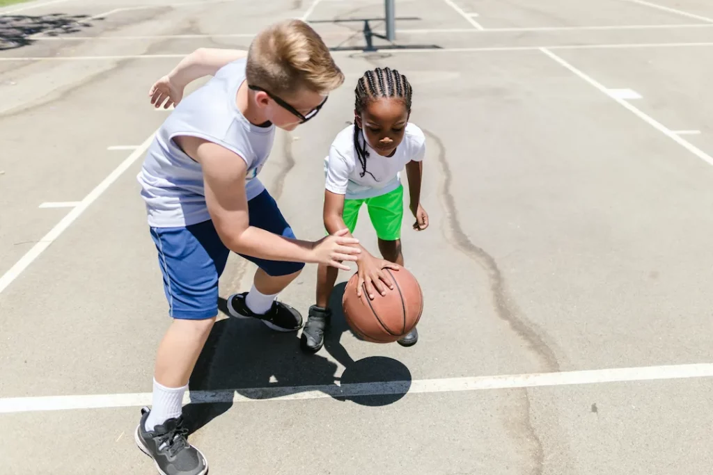 Sports activities for preschoolers includes two children playing with a basketball, as pictured here. 
