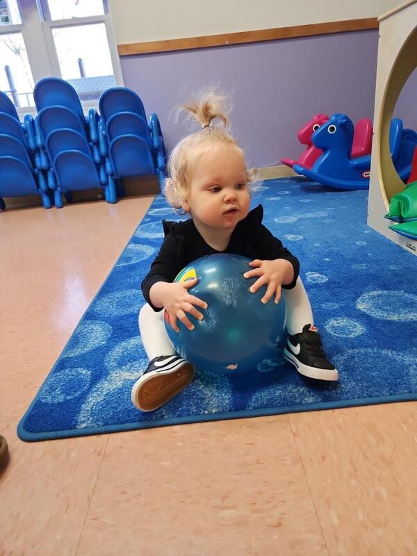 A young girl playing with a ball in a classroom. Raleigh infant care.