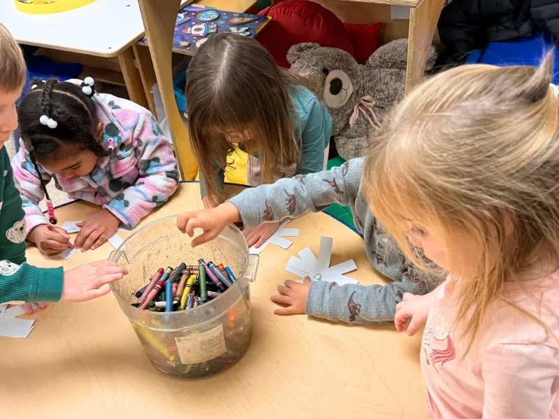 Children drawing with crayons at one of the best Raleigh preschools