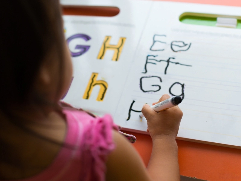 Young girl learning to write letters. Image complements the blog: What is TK vs. Pre K?