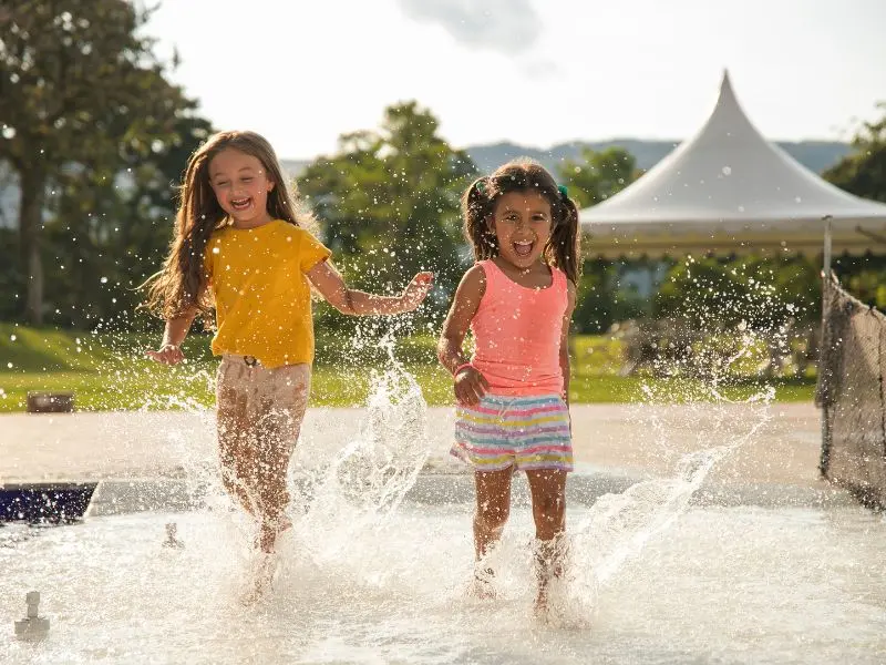 Two girls play in water. Image is for the blog "easter activities for preschoolers."