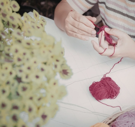 child crafting with red yarn and flowers, highlighting preschool nature activities, nature activities for kids, nature lesson plans for preschoolers, nature activities for preschoolers, nature preschool activities.