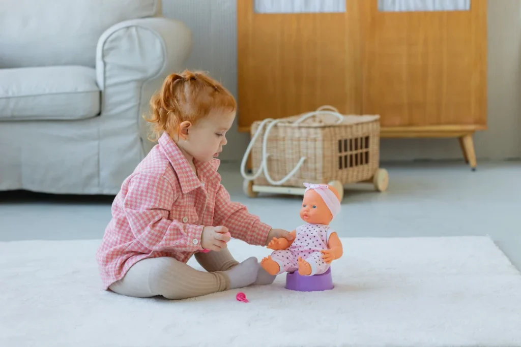 toddler engaging with a doll on a cozy carpet in a modern living room setting.. Image complements the blog: how to potty train. 