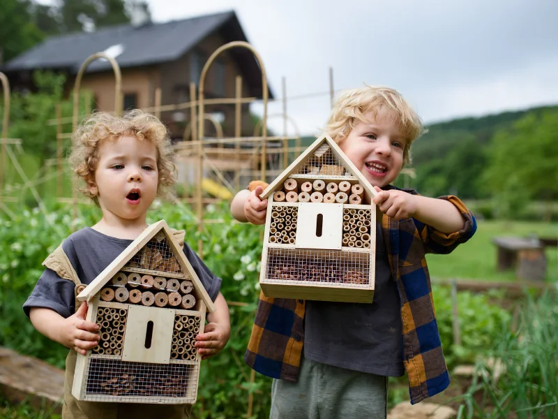 young boy and girl hold an insect hotel in the garden as part of outdoor stem activities