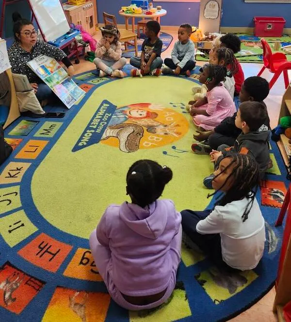 Classroom of children sitting on a rug. Image accompanies the page "Kindergarten Readiness Raleigh." 