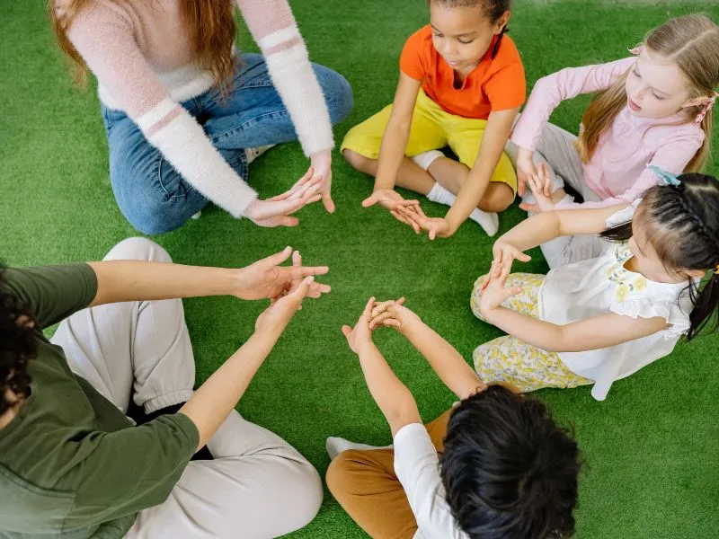 music for preschoolers for social skills as shown here by preschoolers in a circle with hand signs