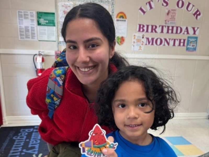 A mom and child smiling in a classroom. This image complements the page titled