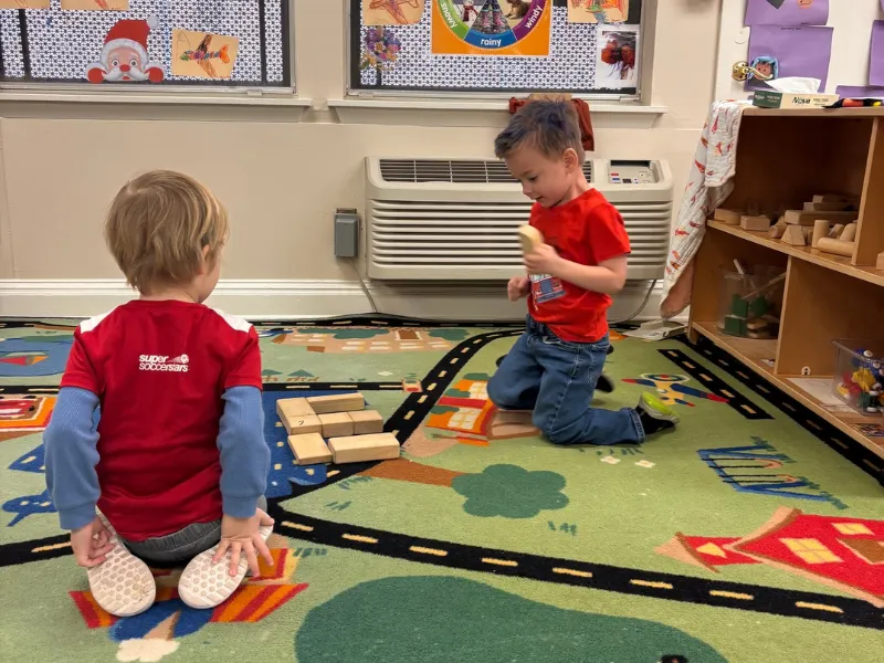 Two boys play with toy trains in a classroom. This image complements the page
