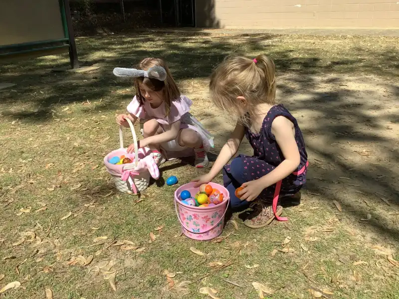 Two girls fill baskets with Easter eggs. This image complements the page titled "Pre K Program in Raleigh, NC."