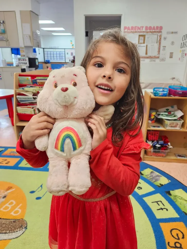 Female child holding a care bear. Image complements the blog "preschool checklist for parents." 