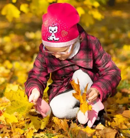 child examining a leaf, highlighting preschool nature activities, nature activities for kids, nature lesson plans for preschoolers, nature activities for preschoolers, nature preschool activities.