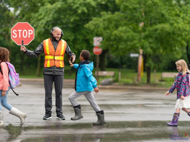 A crossing guard with a stop sign directing children. This image complements the blog addressing road safety for kids. 