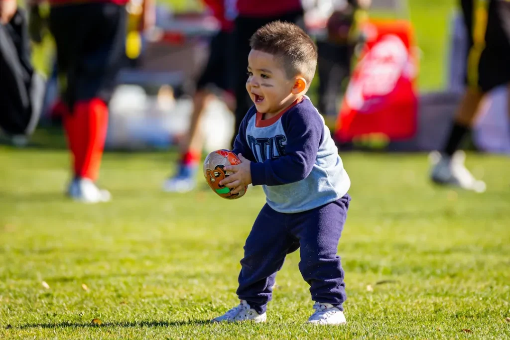 A young male child holding a small football. This image accompanies the blog titled, "Sports Activities for Preschoolers."
