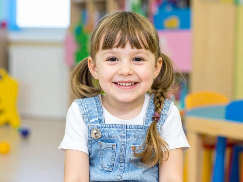 Young girl with pigtails in classroom. Image complements the blog: tk vs. pre k vs kindergarten.