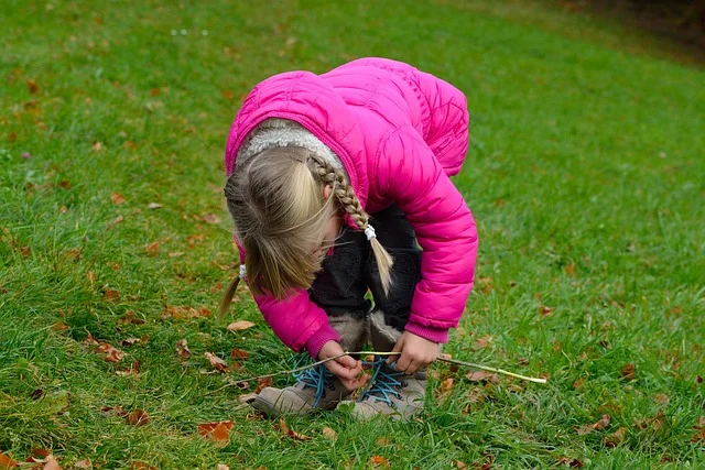 adult helping child practice tying shoelaces on sneakers